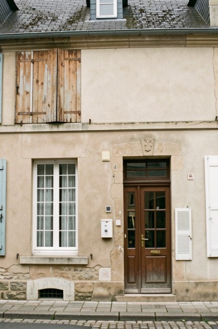 Façade réaliste d’une ancienne maison française dans une rue patrimoniale, avec des fenêtres en bois traditionnelles comparées à des fenêtres modernes en PVC.